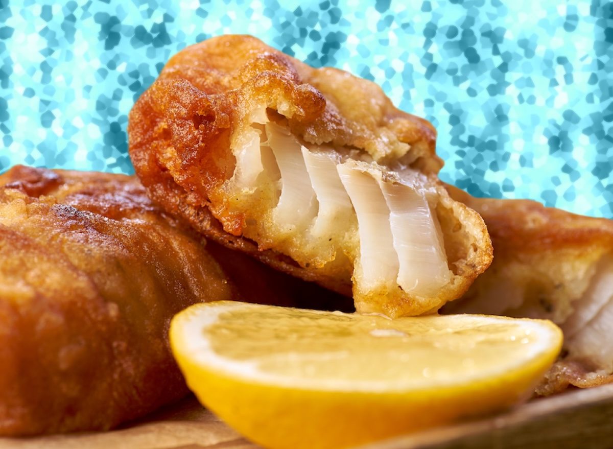Um peixe frito crocante e fresco, com fios de azeite dourado, sobre uma toalha de linho branco