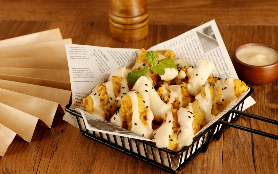 Peixe frito crocante ao lado de batata‑doce dourada, servido em prato branco com limão e folhas verdes