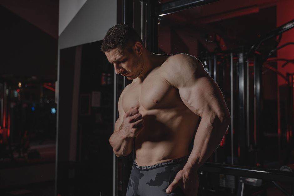 Kris Gethin ao lado de frascos de peptídeos, halteres de alto volume e um modelo 3D de célula‑tronco