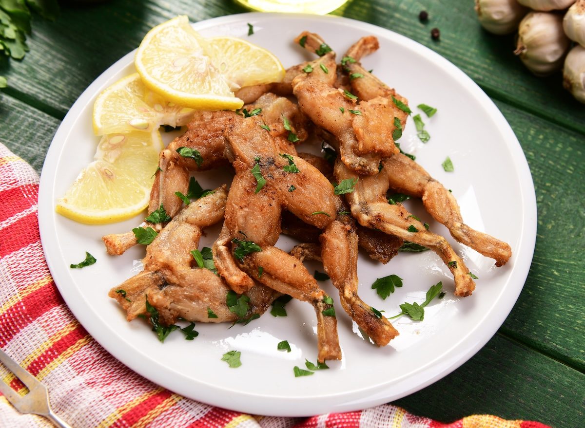 Prato com pernas de rã fritas ao lado de salada verde, limão e um haltere ao fundo