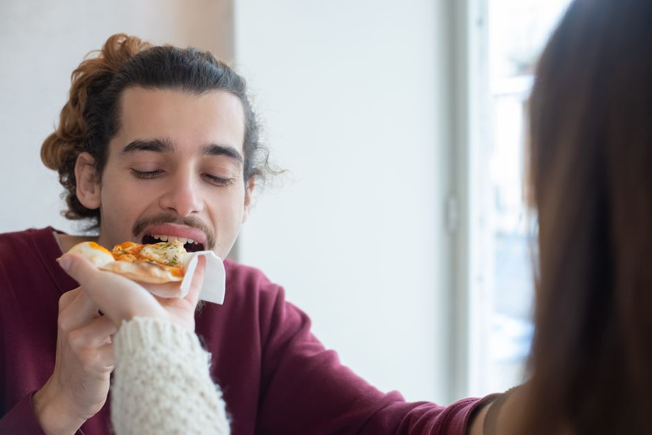 Uma pizza de borda grossa com massa alta e crocância, coberta por molho e queijo derretido
