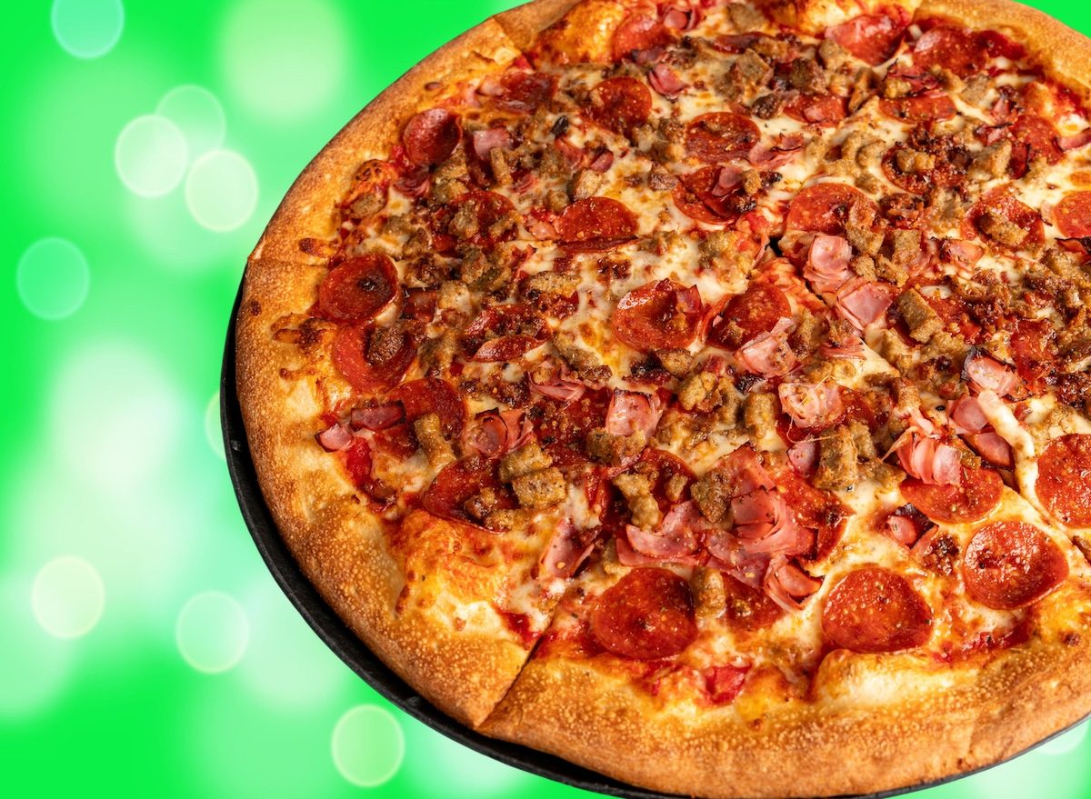 Uma pizza de carne com ingredientes frescos, legumes e queijo leve em cima de uma massa caseira saudável
