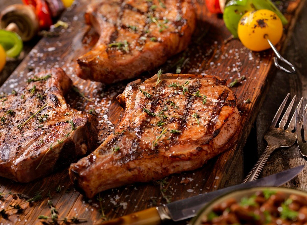 Pork chop grelhado ao ponto ao lado de um cornbread dourado, acompanhado de brócolis e uma taça de água