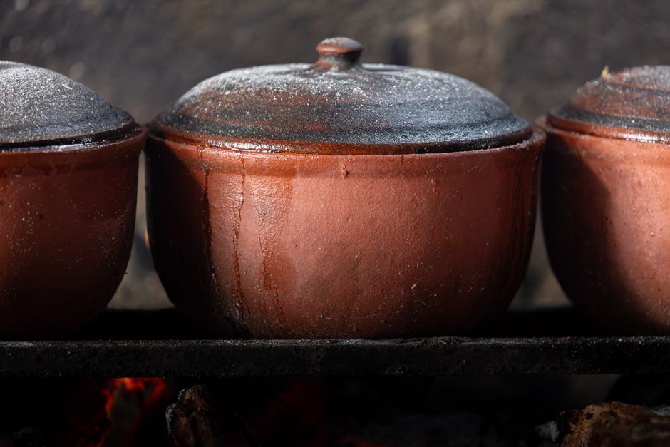 Uma carne de boi assada no forno, cercada por cebolas e batatas, com um prato de salada ao lado