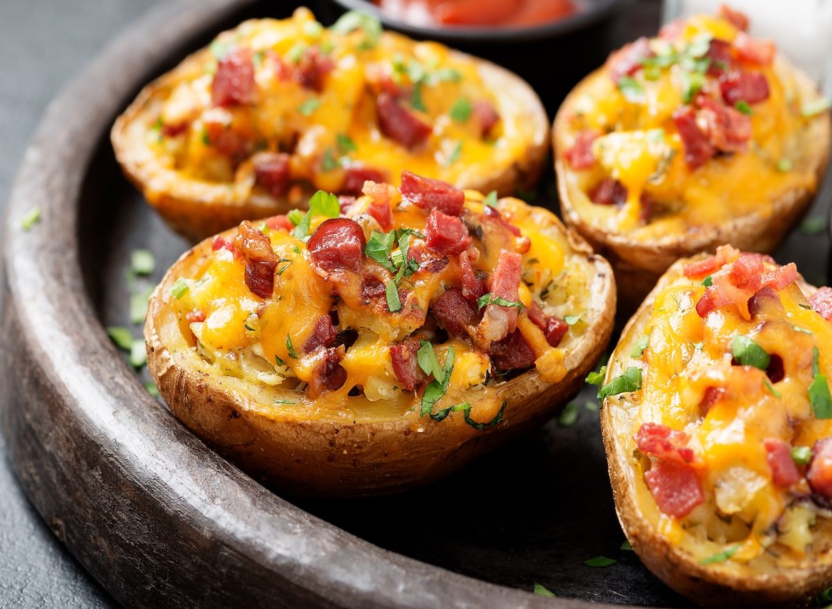 Mãos segurando potato skins crocantes ao lado de uma salada verde e garrafa de água