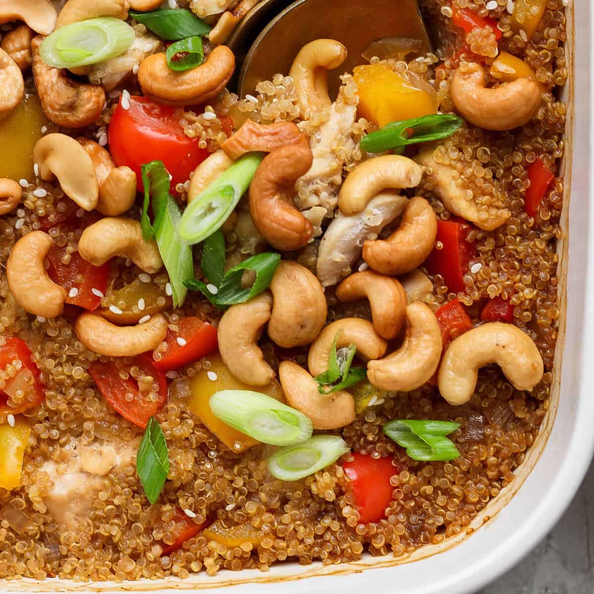 Prato de quinoa com cubos de frango, cenoura, pimentão, molho hoisin, finalizado com castanhas de caju crocantes