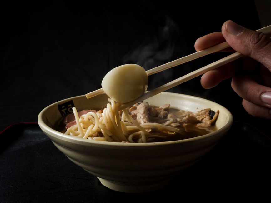 Ramen instantâneo ao lado de brócolis, peito de frango grelhado e um limão espremido, tudo sobre uma tábua de corte