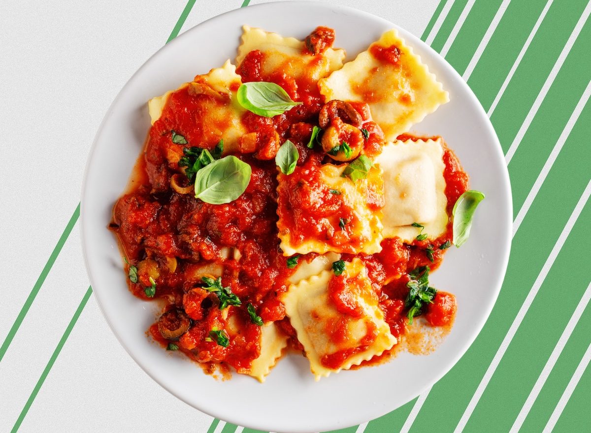 Pessoa segurando um prato de ravioli com molho verde e recheio de frango