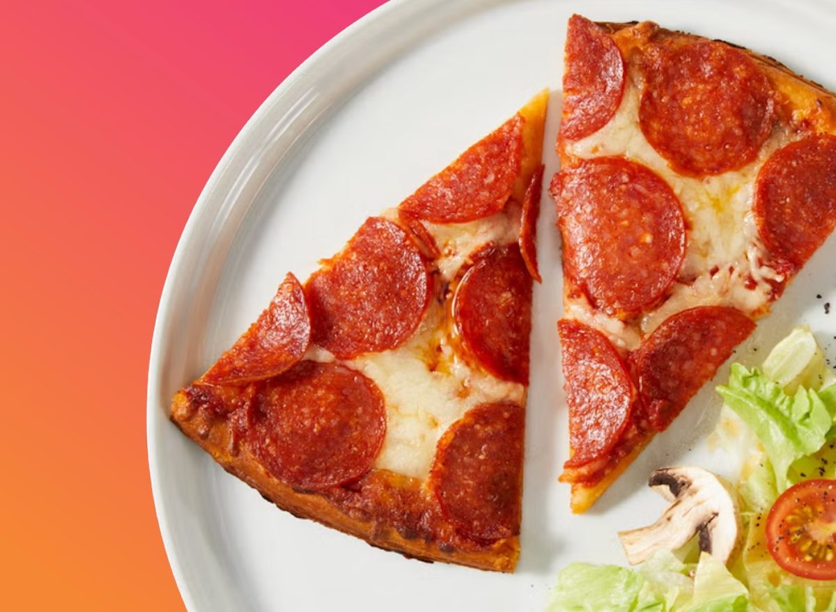 Uma pizza congelada, com molho e queijo derretido, é exibida em um prato com vegetais frescos