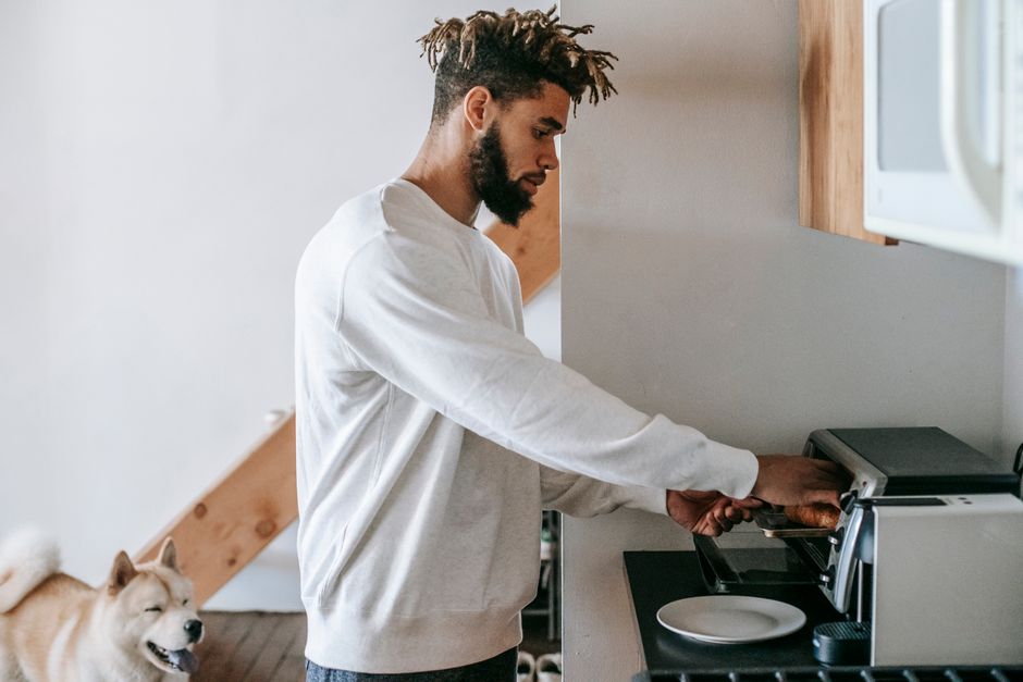 Prato de lasanha congelada ao lado de uma garrafa de água e uma prancha de yoga sobre mesa de cozinha
