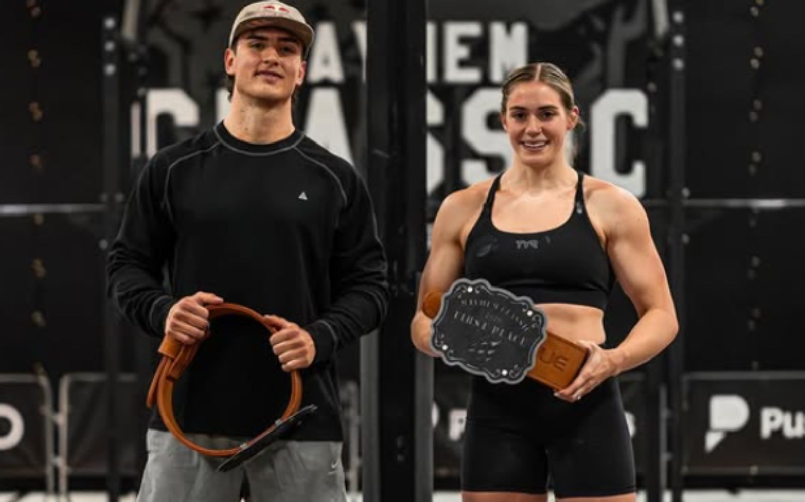Atletas de CrossFit suados realizam um levantamento de peso olímpico com barras e anilhas em uma arena competitiva