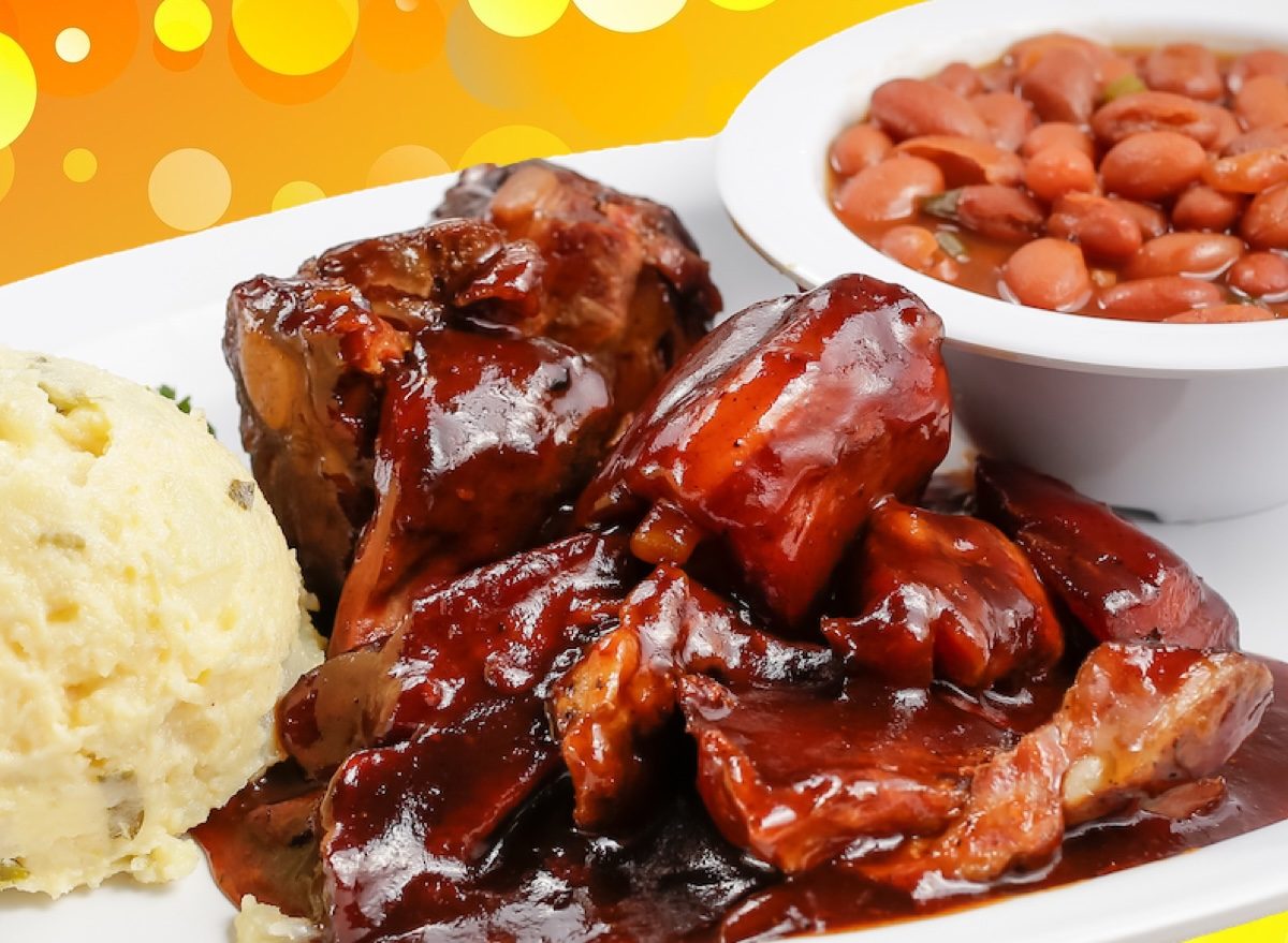 Um prato de rib tips defumados com molho BBQ, com pedaços de carne suína crocantes e uma garrafa de molho ao lado