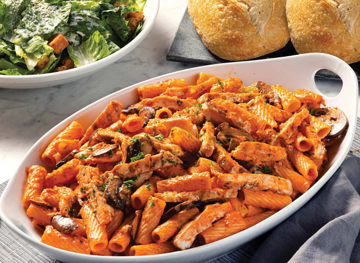 Rigatoni al dente em prato cerâmico, com molho de tomate fresco, manjericão e um ralador de queijo ao lado