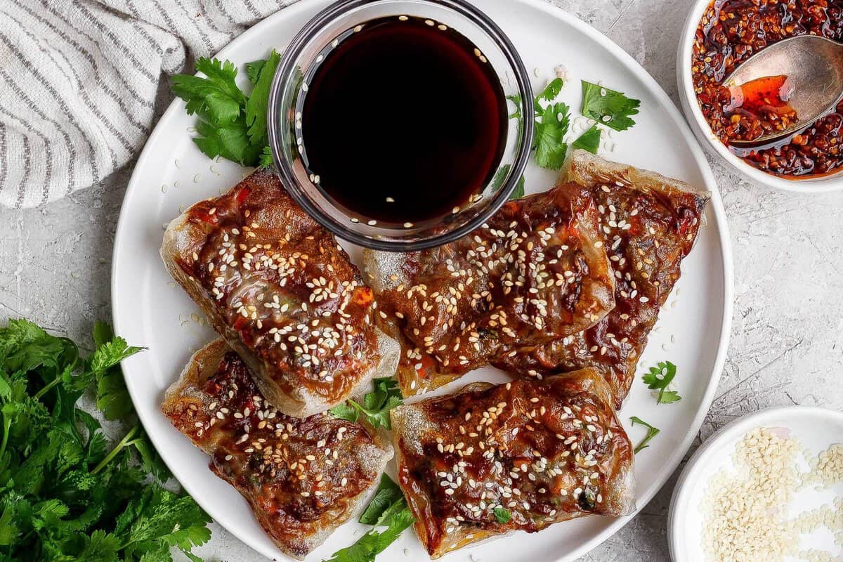 Rolls de carne suculentos com chili crunch dispostos em uma marmita organizada ao lado de halteres e uma garrafa