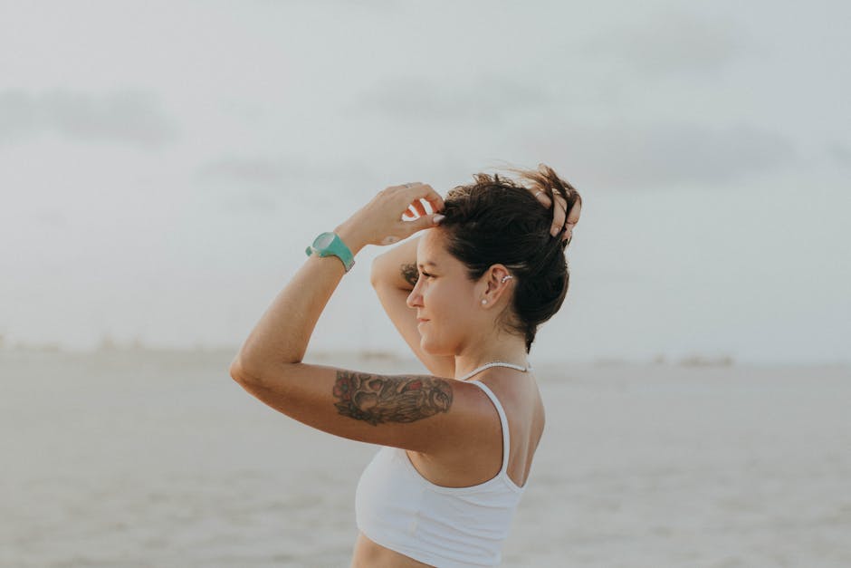 Mulher em pose de yoga, com pernas abertas e mãos segurando um copo de água fresca