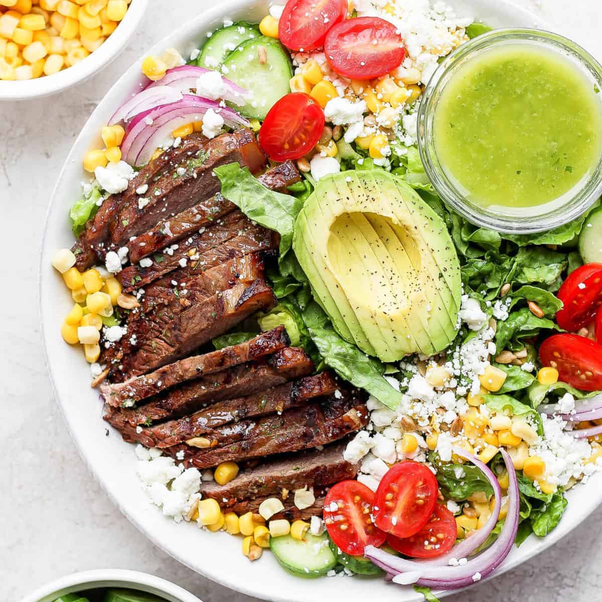 Um pedaço de steak grelhado sobre uma salada de vegetais frescos e legumes variados