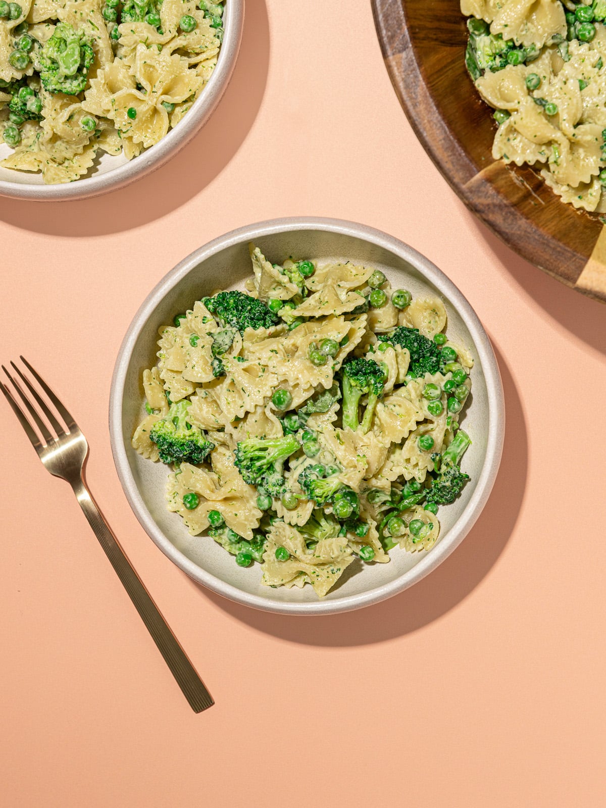 Tigela de salada de macarrão borboleta com brócolis ao molho verde, garfo ao lado e etiqueta 9g de proteína