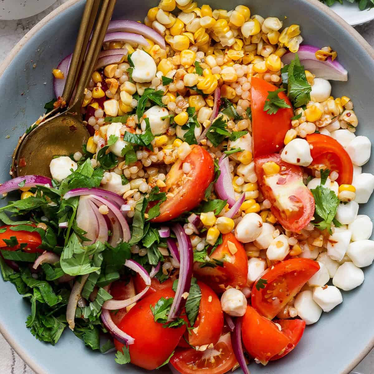 Milho cozido, tomate, mozzarella, amendoim e folhas de alface em uma tigela alegre