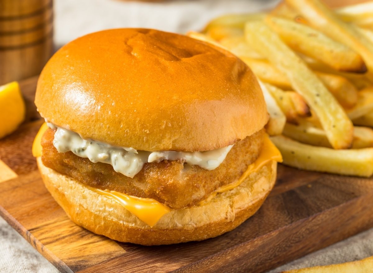 Sanduíche de peixe empanado aberto, com filé dourado, alface, tomate e porção de batatas fritas crocantes ao lado