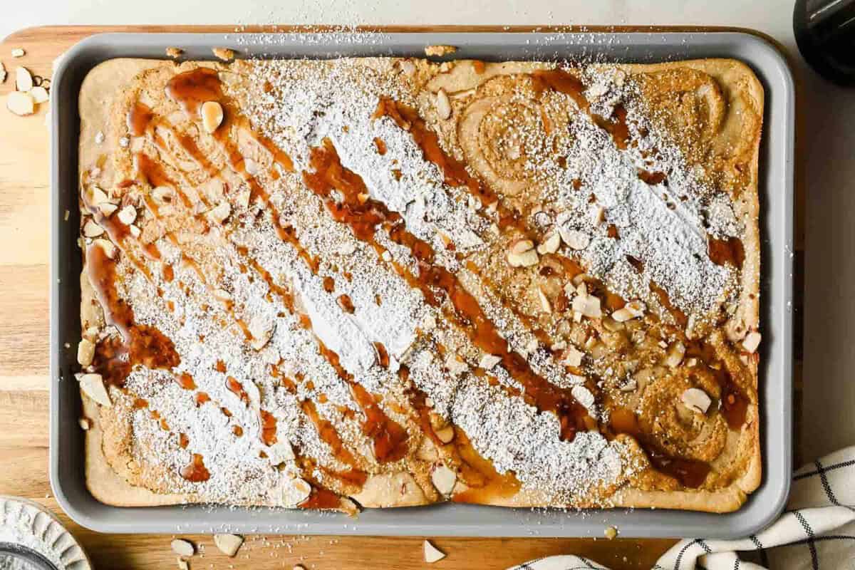 Panquecas douradas de amêndoas em sheet pan, com iogurte grego e frutas vermelhas sobre bancada clara