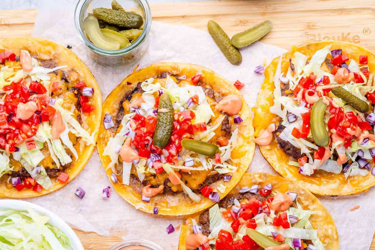 Taco de carne moída com queijo derretido, alface e tomate ao lado de halteres e garrafa de água na bancada