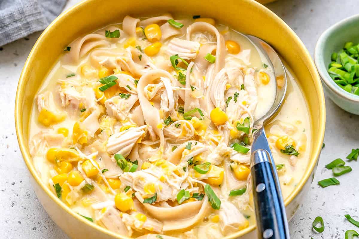 Um frango cozido e fatias de pão de milho em uma tigela de sopa cremosa