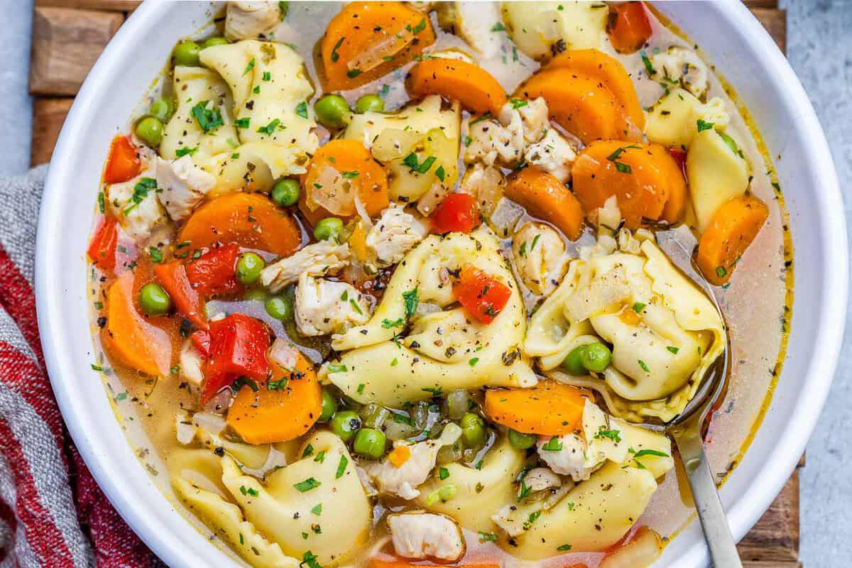 Frango magro, tortellini de queijo e legumes frescos em uma panela de sopa