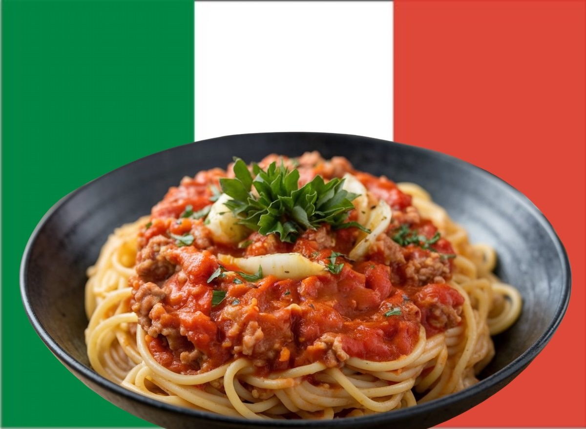 Um prato de spaghetti à bolonhesa com massa al dente, molho de tomate encorpado e carne magra, acompanhado de vegetais frescos e um pouco de queijo parmesão