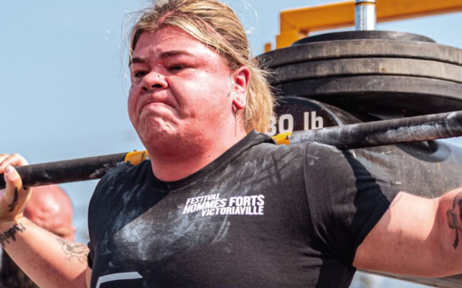 Um atleta de strongman levanta um peso com uma barra de ferro e um grande disco de aço