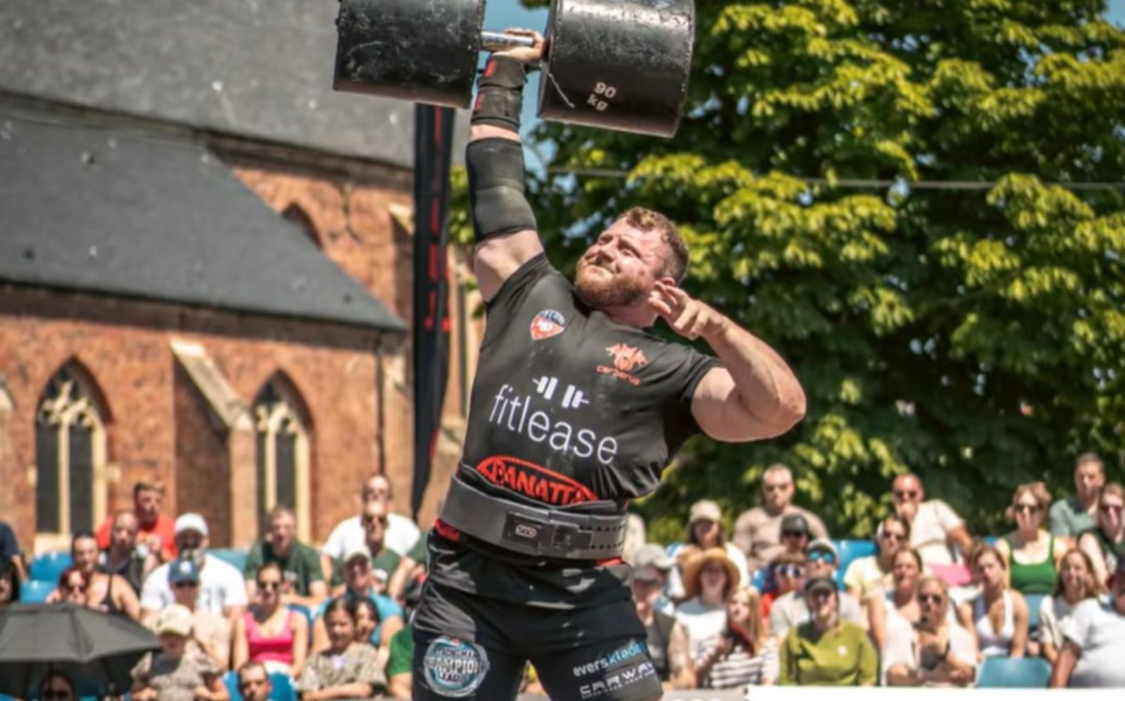 Um homem forçando um peso de 180kg em uma pedra de Atlas, com um visual de suor e esforço facial