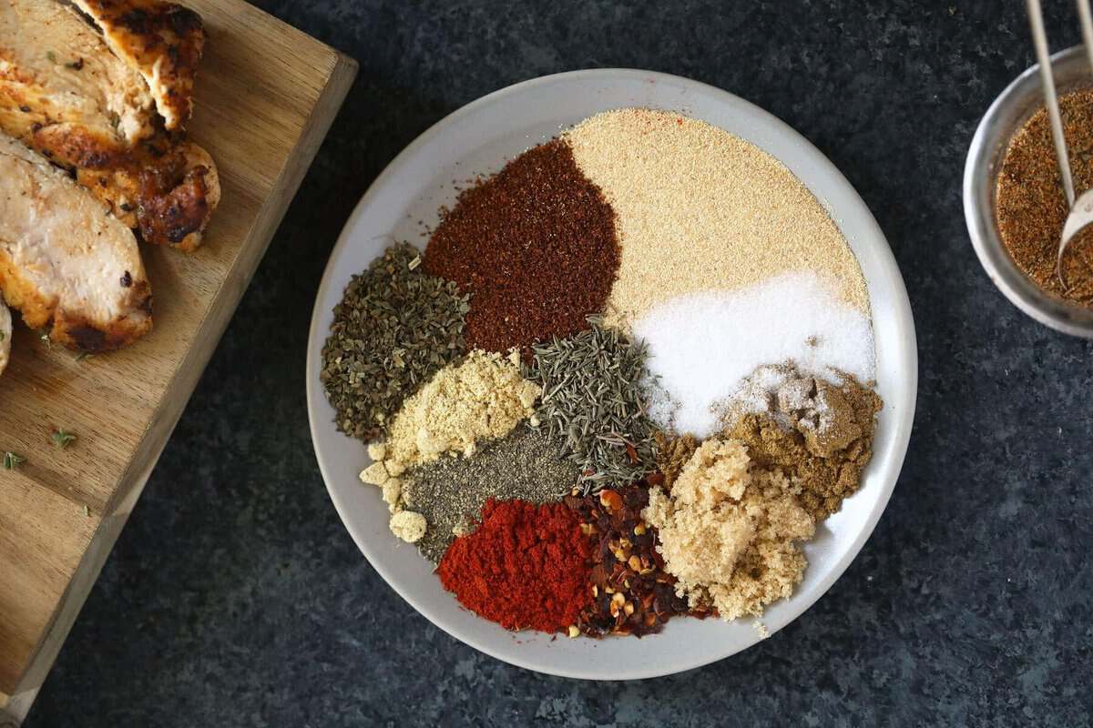 Um prato de frango grelhado com tempero caseiro, alho em pó, páprica doce e cominho, com uma colher de sopa ao lado