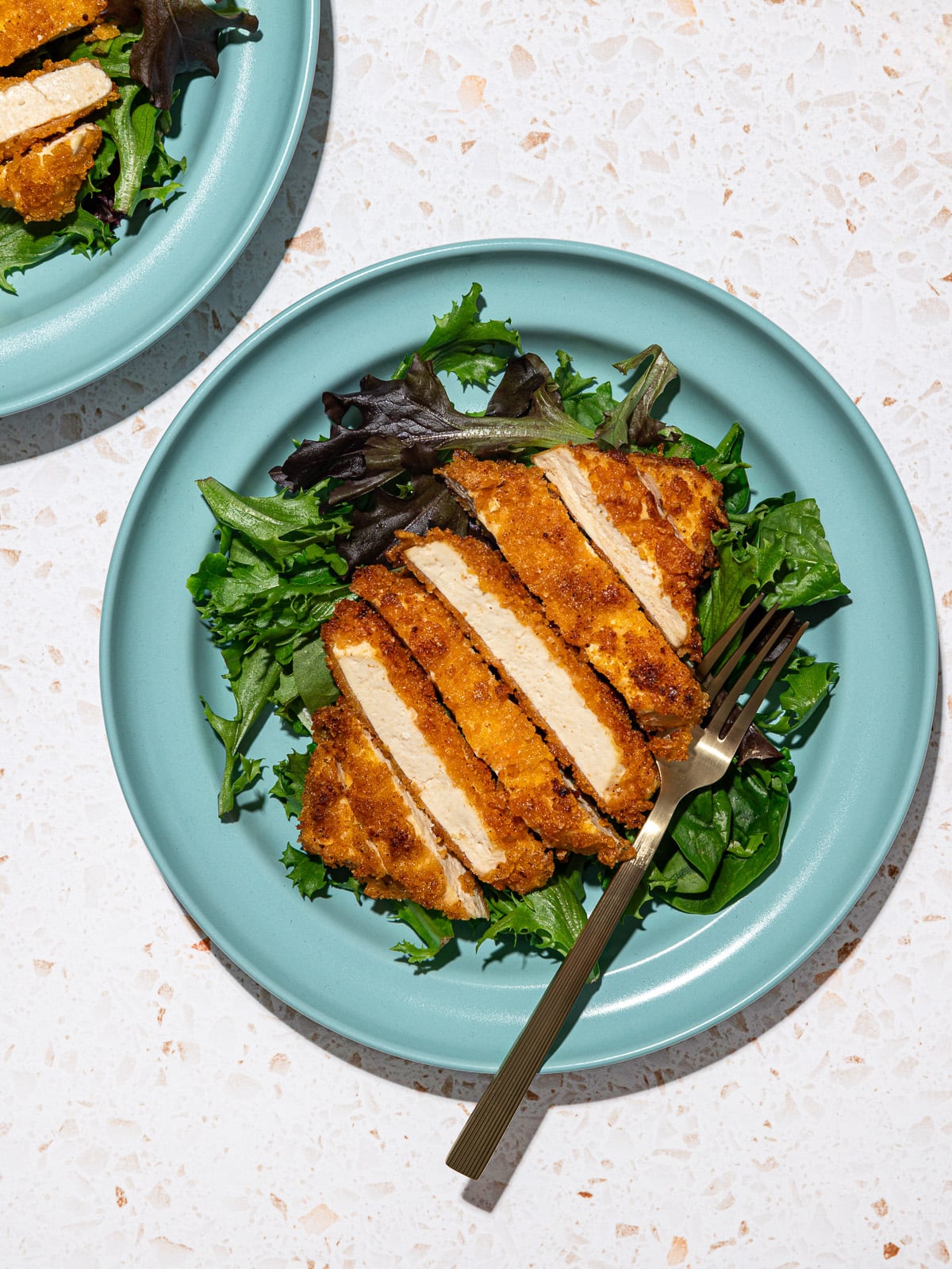 Tofu empanado com milho amarelo, salada verde e batata assada em prato rústico