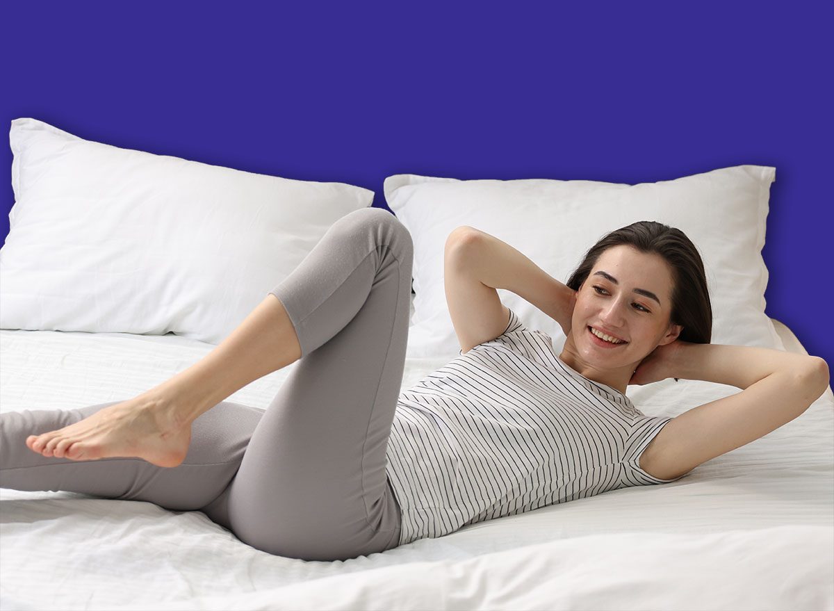 Uma pessoa sentada na cama realiza dead bug march, com os braços estendidos e as pernas dobradas