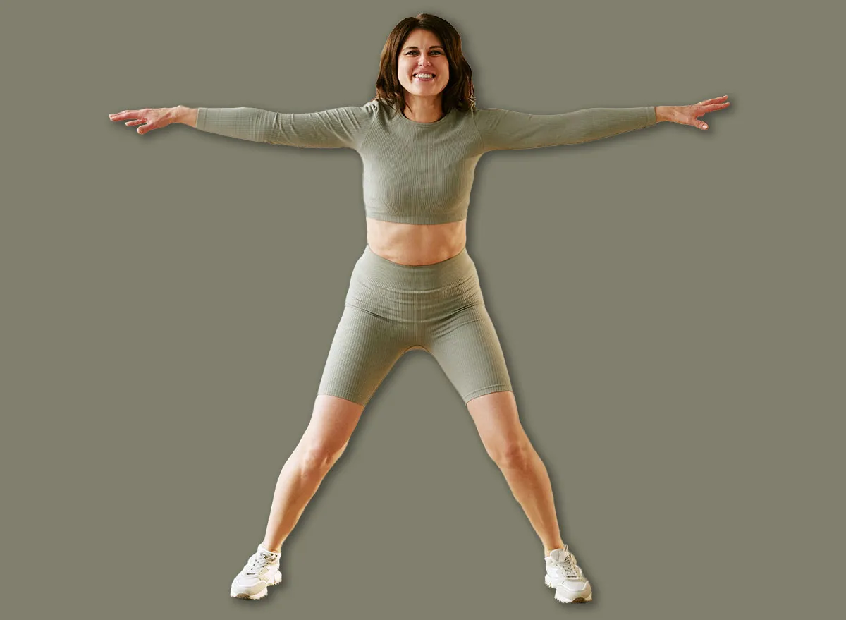 Jovem adulto em roupa esportiva executando agachamento no chão, com cronômetro digital e tapete de yoga ao fundo