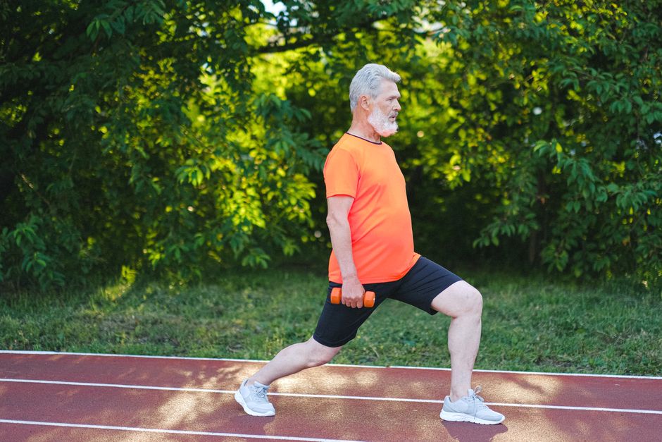 Uma pessoa em pé fazendo uma lunge com um peso de kettlebell na mão
