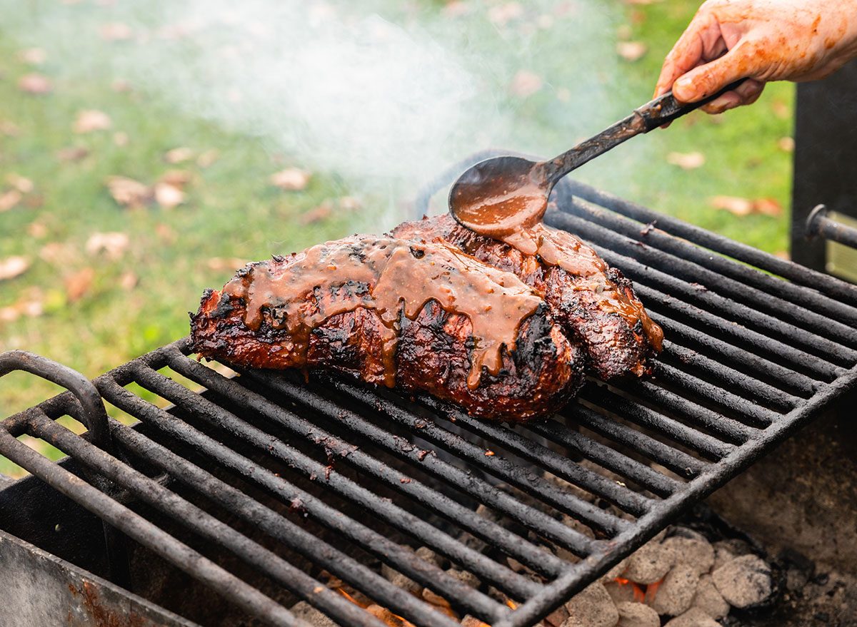 Um steak ribeye grelhado, com bordas crocantes e um corte de tri-tip ao lado, sobre uma toalha de mesa de madeira