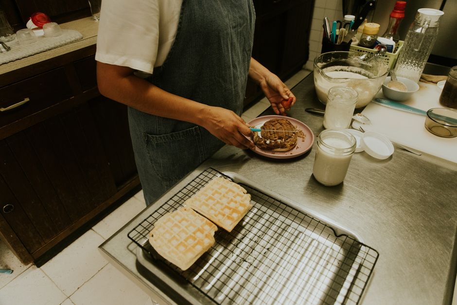 Waffle integral dourado ao lado de frutas vermelhas, amêndoas torradas e um copo de shake proteico